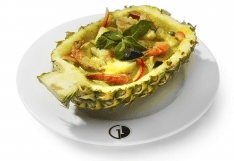 Scampis with green curry in a fresh half pineapple